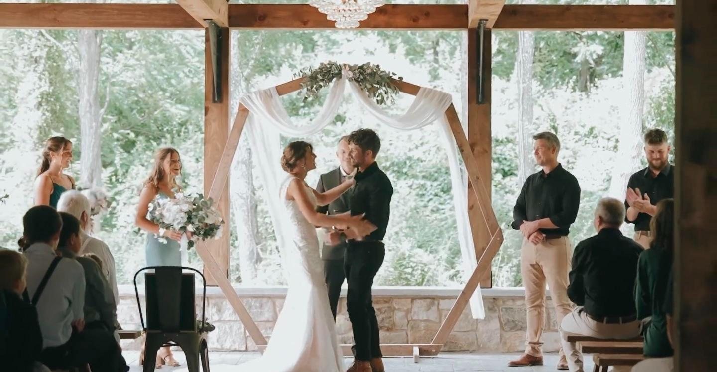 Couple at an outdoor ceremony under a wooden arch