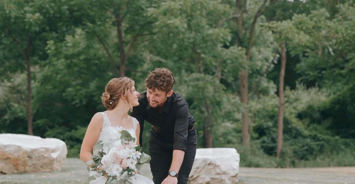 Groom leaning in to his bride by white stones