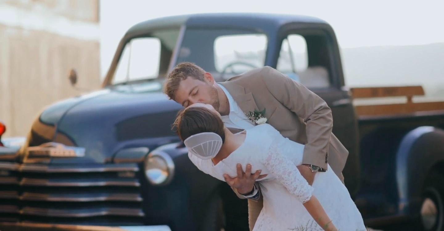 Groom dipping his bride beside a vintage pickup