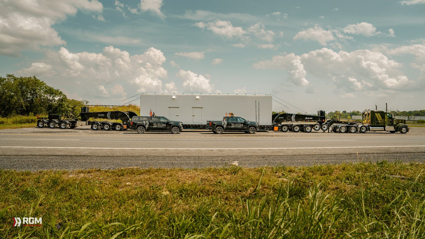 RGM heavy haul convoy with escort trucks and a modular building load